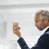 mature-businessman-in-office-examining-rubik-s-cube-e1703675741605.jpg