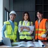 team-of-happy-confiden-engineers-wearing-safety-hard-hat-and-vest-standing-at-site-work-looking-at.jpg